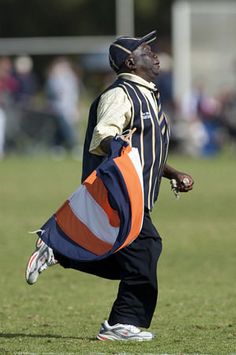 a man holding an orange and blue bag on top of a field