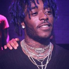 a young man with dreadlocks wearing a black t - shirt and silver necklace