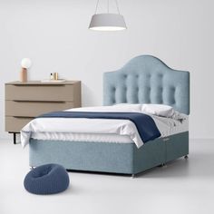 a bed with blue upholstered headboard next to a dresser and night stand