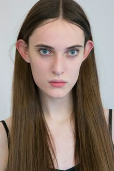 a woman with long brown hair and blue eyes is looking at the camera while wearing a black top