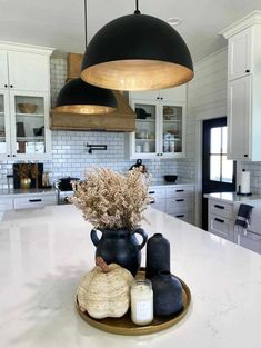 a large kitchen with white cabinets and black pendant lights