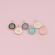 four different colored charms on a pink background