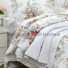 a white bed topped with lots of flowers next to a night stand and nightstands