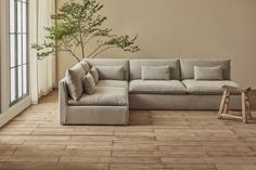 a living room with a sectional couch and wooden flooring next to a large window