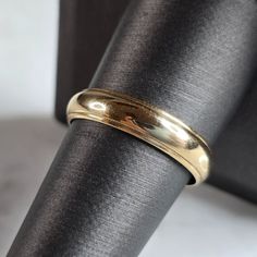 a gold wedding band on top of a black cloth