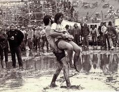 two people are hugging in the mud while others watch from the stands at an event