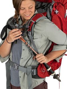 a woman with a backpack on her back is looking at her cell phone and smiling