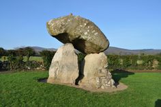 a large rock sitting on top of a lush green field