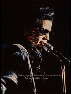 a man with sunglasses on singing into a microphone