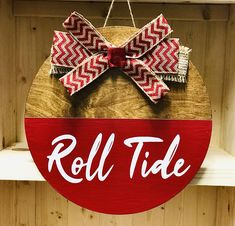 a red and white sign that says roll tide hanging from a shelf in a store