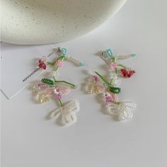 three small crocheted flowers are attached to the back of earwires on a white surface