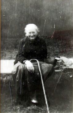 an old black and white photo of a woman sitting on a bench with a cane