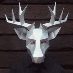 a man wearing a paper mask with horns on his head and the face is made out of white origami