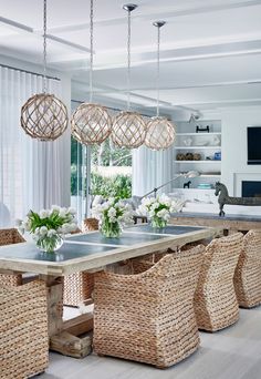 a dining room with wicker chairs and table in the foreground is an open living area