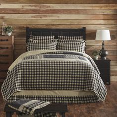 a black and white checkered comforter on a bed in a room with wooden walls