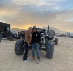 two people standing in front of an off road vehicle