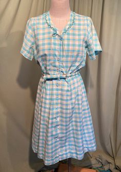 This is a sweet vintage dress from the 50s. No labels or tags. The bust measures 42", waist 32" see measurements below.  Made of turquoise blue, lime green & white plaid cotton. The blue is a little brighter than the photos show.  The dress is not lined.  It is short sleeve with a fitted bodice & flared skirt. The neckline is a V neck with scalloped, pin pleater ruffle trim, along with a little string bow. At the waist seam there are two fabric belt loops & the matching fabric covered belt. The buckle is fabric covered & has discolored with age. Buttons all the way down the front with clear faceted plastic buttons. The buttons are all replacements but are from the same era.  The dress is in very good condition, no damage.  I don't see any spots of stains. A previous owner took up the waist Light Blue Retro Summer Dress, Retro Light Blue Summer Dress, Vintage Light Blue Cotton Dress, Light Blue Vintage Cotton Dress, Vintage Light Blue Knee-length Dress, 1950s Style Blue Vintage Summer Dress, Retro Blue Vintage Dress With Short Sleeves, Blue Retro Vintage Dress With Short Sleeves, Vintage Blue Summer Dress