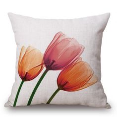 three pink and orange tulips on a white linen pillow cover with green stems