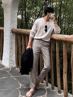 a man standing on a porch talking on a cell phone and holding a bag in his hand