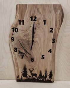 a clock made out of wood with deer and trees in the woods on it's face