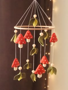 a close up of a mobile with mushrooms on it's sides and leaves hanging from the ceiling