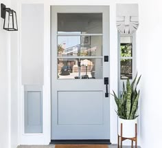 the front door is painted white and has a potted plant