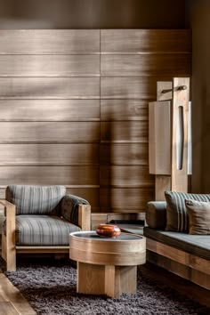 a living room with two couches and a coffee table in front of a wood paneled wall