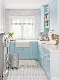 a laundry room with blue cabinets and white tile on the floor, along with a washer and dryer