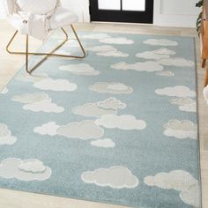 a blue rug with clouds on it in front of a door and chair next to the doorway