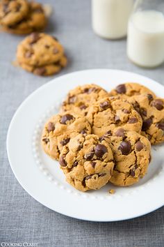 chocolate chip cookies on a white plate next to milk