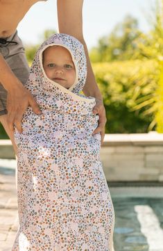 a baby wrapped in a blanket by the pool