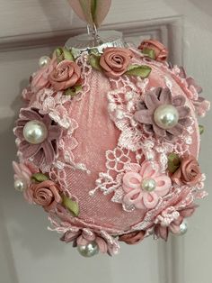 a pink ornament with flowers and pearls hanging on a doorknott