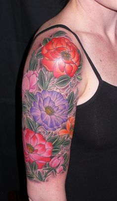 a woman wearing a black tank top with flowers on her arm