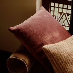 two pillows sitting next to each other in front of a window