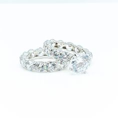 two white gold wedding rings with diamonds on each one and an oval cut diamond in the middle