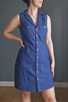 a woman standing in front of a wall with her hands on her hips wearing a blue dress