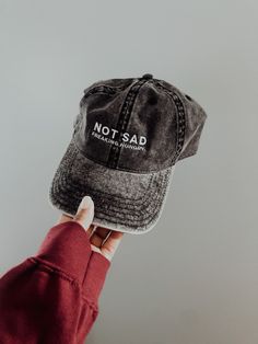 DETAILS: Embroidered text on vintage wash dad cap. One-size fits all. MATERIALS: 100% cotton twill; 6-panel unstructured cap with a low profile; 6 sewn eyelets; black sweatband; metal snap buckle with an antique brass finish; washed-out vintage effect. CARE:Machine Wash, Cold, Non-Chlorine Bleach When Needed, Tumble Dry, Normal, Low Heat, Do Not Iron, Do Not Dry Clean. COLOR:Hat is in the color vintage wash charcoal. Embroidery is in white.PROCESSING:Since all purchases are made to order, proces Black Distressed Dad Hat, Black Distressed Dad Hat Baseball Cap, Distressed Black Dad Hat Baseball Cap, Distressed Black Dad Cap, Adjustable Distressed Black Dad Hat, Black Distressed Dad Hat One Size, Distressed Black Dad Hat, Distressed Adjustable Dad Hat In Cotton, Distressed Adjustable Cotton Dad Hat