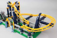 a toy roller coaster made out of legos on a white surface with yellow and blue trim