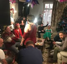 a group of people sitting around in a living room with christmas decorations on the walls