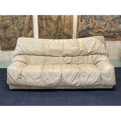 a white futon couch sitting on top of a blue floor next to two paintings