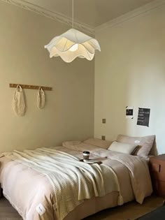 a bed sitting in a bedroom next to a wooden dresser under a hanging light fixture