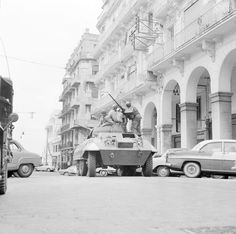 an old black and white photo of men on top of a tank in the street