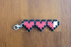 three heart shaped beads are attached to a keychain on a wooden surface,