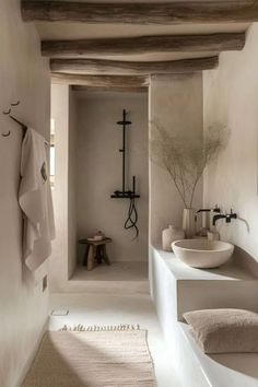 a white bathroom with two sinks and a bathtub in it's center, along with towels hanging on the wall