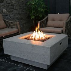 a fire pit sitting on top of a black tile floor next to two couches