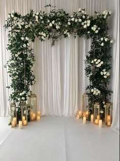 a white wedding arch with candles and flowers