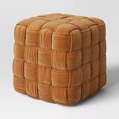 a square foot stool made out of brown suede material with squares on the top