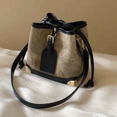 An elegant lingering sound that transcends the times. A bucket bag that can hold your smartphone, wallet, and makeup pouch. The combination of the dark and light body and the jet black leather is exquisite. The decorated leather tag adds a touch of playfulness. You will be fascinated by the delicate details. 
 
 
 Size 
 
 
 FREE size 
 
 Height: 16.5cm 
 Width: 17cm 
 Depth: 11cm 
 
 
 
 
 
 Material 
 
 Leather 
 Rayon Portable Black Bucket Shoulder Bag, Portable Black Shoulder Bucket Bag, Leather Bucket Bag With Mobile Phone Bag, Luxury Bucket Bag With Mobile Phone Bag For Everyday, Luxury Bucket Bag With Mobile Phone Holder For Everyday, Elegant Large Capacity Phone Bag For Travel, Large Capacity Bucket Phone Bag For Daily Use, Daily Use Bucket Bag With Mobile Phone Pouch, Trendy Leather Bucket Bag With Mobile Phone Holder