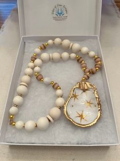 a white and gold beaded necklace in a box