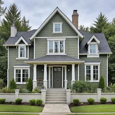 a large gray house with white trim and two story windows on the second floor is surrounded by greenery